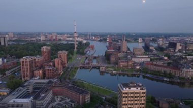 Alacakaranlıktaki Rotterdam kentinin hava manzarası, liman, modern binalar ve kentsel ufuk çizgisine karşı ikonik Euromast Kulesi.