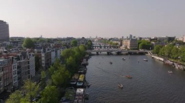 Amsterdam 'ın sakin hava manzarası, ikonik kanalların üzerinde süzülüyor motorlu teknelerle ve şehrin tarihi binalarıyla.