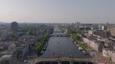 Amsterdam 'ın cazibesi kuş bakışı tekneler kanallarda dolaşırken ve insanlar ikonik mimari ve köprülerde dolaşırken.