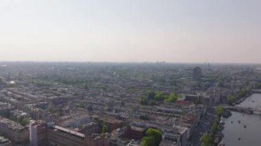 Amsterdamlar kuş bakışı bir görünüme sahip, kanallarını, parklarını ve şehir manzarasını açık bir gökyüzü zeminine yansıtıyor..