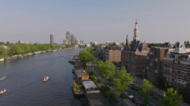 Amsterdam kanallarında yüzen tekneler ve tarihi ve modern binalardan geçen motorlu tekneler. Seyahat ve turizm projeleri.