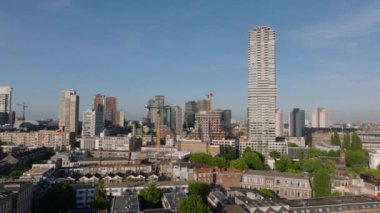 Rotterdam 'ın gökdelenlerle ve güneşli bir günde yeşil alanlarla gökyüzü manzarası. Kentsel planlama, mimari ve şehir hayatı temaları.