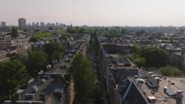 Amsterdam manzaralı çatılar, ağaç sıralı sokaklar, ve canlı şehir hayatı, resimli mimari ve kentsel ufuk çizgisi.