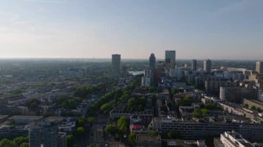 Rotterdam 'lar gökdelenler, yüksek binalar, ağaç sıralı caddeler ve açık bir gökyüzü altında kentsel yerleşim, şehir manzaraları ve mimari sergileniyor..