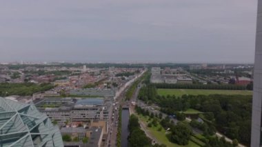 Parçalı bulutlu gökyüzünün altında ufukta uzanan binalar, parklar ve yollarla Lahey şehir manzarası.