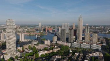 Gökyüzünden Rotterdam şehri ikonik binalar, Erasmus köprüsü ve Nieuwe Maas nehri açık mavi gökyüzü altında sergilenmektedir..