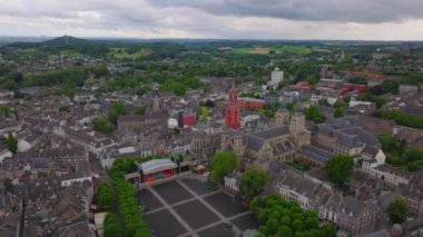 Maastricht şehir merkezinin havadan görünüşü Saint Jans kilisesi, tarihi mimarisi ve bulutlu bir gökyüzü altında yemyeşil..