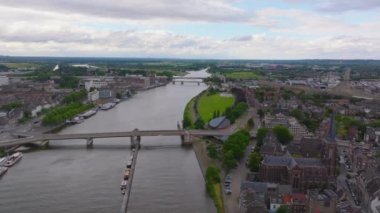 Köprüleri olan Maastricht 'in hava manzarası, yeşil manzaralar, ve parçalı bulutlu bir günde nehir boyunca tarihi binalar. Şehir manzarası ve manzaralı gökyüzü.
