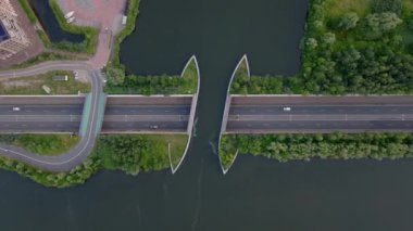 Yazın yemyeşil yeşilliklerle çevrili bir Hollanda kanalı altındaki modern bir karayolu köprüsünün havadan görünüşü, kentsel altyapı ve ulaşımı gözler önüne seriyor.