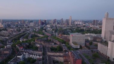 Rotterdam 'ın günbatımında şehir manzarası yollar, yerleşim yerlerindeki binalar ve modern şehir silueti ön plana çıkıyor..