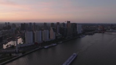 Gün batımında nefes kesen Rotterdam silueti, akşam ışığında parlayan gökdelenler ve aşağıda akan sakin nehirler..