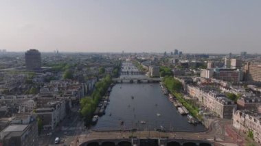 Amsterdam 'ın cazibesi kuş bakışı tekneler kanallarda dolaşırken ve insanlar ikonik mimari ve köprülerde dolaşırken.