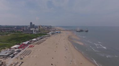 Turizm ve seyahat temaları için güneşli bir günde, rıhtım, kumlu sahil ve yüksek binalarla Lahey sahilinin havadan görünüşü.