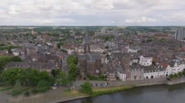 Kuşbakışı manzaralı Maastricht şehrinin tarihi çatıları, antik yapıları ve manzaralı nehir manzarası sergilenmektedir..