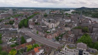 Maastricht şehir manzarası nefes kesici, tarihi binalar, dolambaçlı sokaklar, yemyeşil ağaçlar ve manzaralı bir nehir manzarası var..