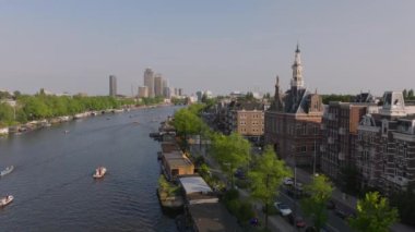 Amsterdam kanallarında yüzen tekneler ve tarihi ve modern binalardan geçen motorlu tekneler. Seyahat ve turizm projeleri.