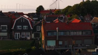 Hollanda, Urk 'taki yel değirmenlerinin ve Hollandalı evlerin havadan görünüşü. Rüzgar türbinleri günbatımı gökyüzüne karşı, yeşil ağaçlarla çevrili..