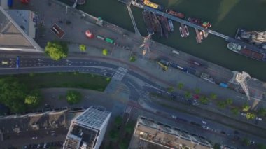 Rotterdam 'ın merkezindeki binalar ve yeşilliklerle çevrili bir kanaldaki teknelerin hava görüntüsü. Bir Hollanda şehrinin canlı şehir manzarası.