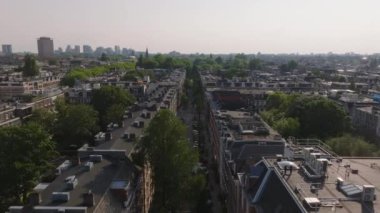 Amsterdam manzaralı çatılar, ağaç sıralı sokaklar, ve canlı şehir hayatı, resimli mimari ve kentsel ufuk çizgisi.