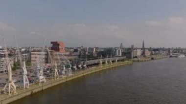 Antwerp, Belçika 'nın canlı şehir manzarası, Scheldt Nehri' ni gözler önüne seriyor. Liman vinçleri ve çarpıcı bir zemin üzerine kurulu kentsel bir siluet..