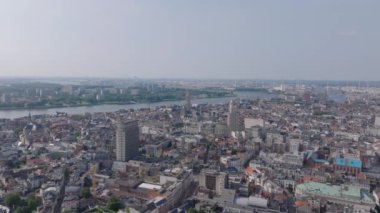 Antwerp ufuk çizgisi ve Scheldt Nehri parlak, güneşli bir gökyüzü altında tarihi ve modern mimariyi harmanlayan canlı bir şehir manzarasını gözler önüne seriyor..