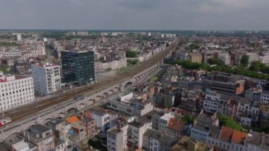 Belçika 'nın Antwerp kentindeki birçok bina ve tren yolu bulunan yoğun bir şehir manzarası. Sokakta arabalar sürüyor ve bazı bitkiler görünüyor..