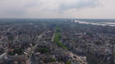 Hava görüntüsü Antwerps şehir merkezini sergiliyor ve Scheldt Nehri 'ni yavaş yavaş gözler önüne seriyor. Sahne, güneşli bir gökyüzünün altında canlı bir şehir manzarası yakalıyor..