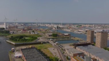 Antwerps ufuk çizgisi ve Scheldt Nehri parlak, güneşli bir gökyüzü altında tarihi ve modern mimariyi harmanlayan canlı bir şehir manzarasını gözler önüne seriyor..