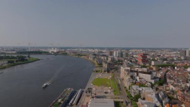 Scheldt Nehri boyunca yüzen teknelerin yer aldığı havadan görüntüler Antwerps şehir merkezini vurguluyor. Ufuk çizgisi tarihi ve çağdaş mimarinin bir karışımını sergiliyor..