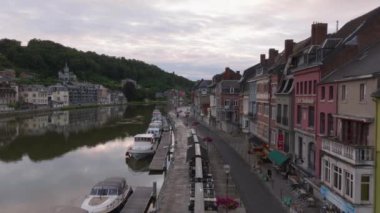 Havadan bakıldığında, Belçika 'nın Dinant kentindeki Meuse nehri ve renkli binalar ön plana çıkıyor. Nehir kıyısında yüzen tekneler huzurlu ve büyüleyici bir atmosfer yaratır..