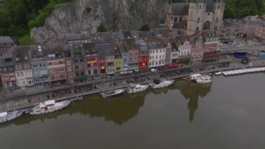 Belçika 'nın Dinant şehrinde, Meuse Nehri' nin kıyısındaki Collegiate Kilisesi 'nin yanındaki renkli binalar. Nehir kıyısındaki kayıklar.