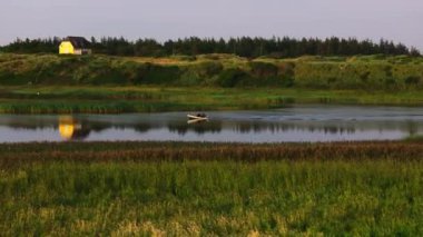 Balıkçı teknesini Danimarka 'daki bir nehrin sakin sularına götürür. Güneş batar ve yeryüzüne sıcak bir ışıltı saçar..