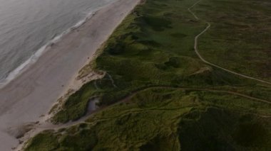 Kuzey Denizi 'ndeki dalgaların Danimarka' daki Ringkobing Fjord 'un kumlu kıyılarına çarptığını gösteren hava görüntüleri, açık mavi gökyüzünün altındaki sahil şeridinin sakin güzelliğini gözler önüne seriyor..