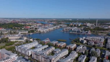 Stockholms yerleşim yerlerinin üzerinden akan güneş ışığı açık bir yaz gününde canlı bir atmosfer yaratır. Tekneler pırıl pırıl suda sorunsuzca süzülür.