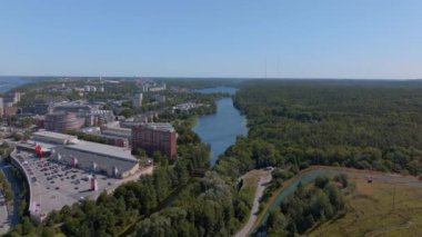 Stockholm 'un binalar, bir göl ve bir ormanla çevrili havadan manzarası. Kamera soldan sağa dönüyor, şehre farklı açılardan bakıyor..