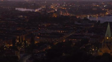 Stockholm ufuk çizgisi aydınlık binalar ve gün batımında canlı araba trafiği ile parıldıyor, çarpıcı, renkli bir gökyüzü ile çerçevelenmiş, şehirlerin cazibesini ön plana çıkarıyor..
