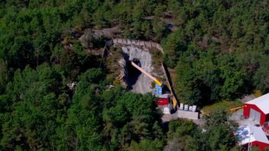 Stockholms ormanlarında işçilerin dağdaki tünele giren büyük sarı bir boru monte ettikleri bir inşaat alanının havadan görüntüsü..