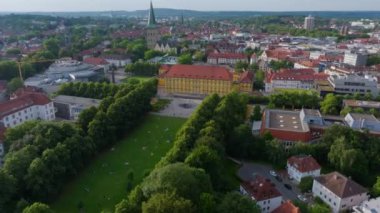 Osnabruck Cathedral dominates the skyline. The University building on the castle stands in in front of its vibrant park populated by students relaxing on a summer day.