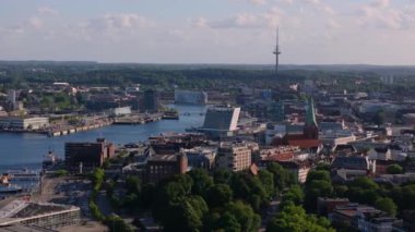 Kamera Almanya 'nın Kiel kentinin üzerinde dönüyor. Kiel fiyortu ve limanı görülebiliyor. Telekomünikasyon kulesi de..