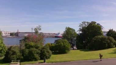 Helsinki 'nin güney limanını gösteren hava görüntülerinde, turistlerin açık mavi gökyüzü altında boş boş gezindiği bir parkın yanındaki Viking Hattı yolcu gemisi görülüyor..