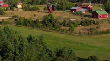Finlandiya 'nın Aland kentindeki canlı yeşil ve sarı alanlar arasında geleneksel kırmızı çiftlik binaları ve yel değirmenini gösteren hava manzaraları, kırsal bölgelerin resimlerini göstermektedir..