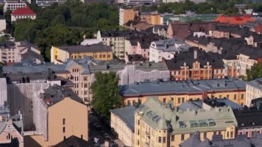 Helsinki, Finlandiya 'da şehir merkezindeki bir mahalleye taşınan kamera renkli binalar, yeşil ağaçlar ve araba dolu caddeler gösteriyor..