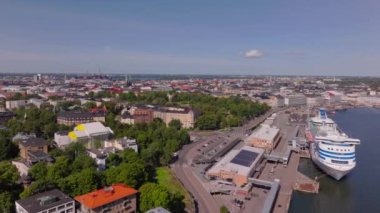 Helsinki, Finlandiya 'da hareketli bir limana yanaşan bir yolcu gemisinin hava perspektifi. Şehir, açık bir yaz gökyüzünün altında uzanıyor..