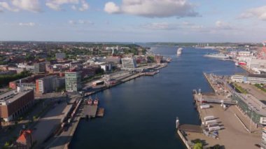 Almanya 'da Kiel limanını gösteren hava görüntülerinde, canlı bir şehir manzarası olan denizde yüzen tekneler yer alıyor. Güneşli gökyüzü ve yaz bulutları Manzaralı güzelliği arttırır.