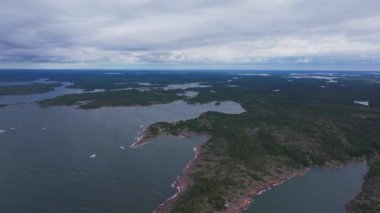Hava manzaraları, çam ormanlarıyla süslenmiş kayalık bir takımada kıyı şeridini sergiliyor. Parlak bir yaz gökyüzü altında gitgide büyüleyici manzaranın üzerinde dönüyor..
