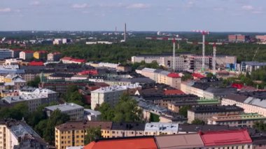 Finlandiya 'nın Helsinki kentinin havadan görünüşü, uzaktaki inşaat vinçleriyle şehir manzarasını gösteriyor. Çevreye kırmızı çatılar ve yeşil ağaçlar hakim..