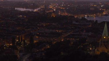 Stockholm ufuk çizgisi aydınlık binalar ve gün batımında canlı araba trafiği ile parıldıyor, çarpıcı, renkli bir gökyüzü ile çerçevelenmiş, şehirlerin cazibesini ön plana çıkarıyor..