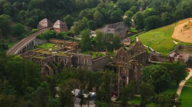 Turistler güneşli bir günün tadını çıkarıyorlar. Villers La Ville Manastırı, yemyeşil ormanların ve çarpıcı antik mimarinin arkaplanına kurulmuş tarihi kalıntılar..