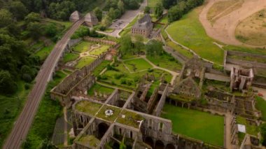 Güneşli bir günde gezen turistlerle Villers Abbey harabelerinin hava manzarası. Solda bir demiryolu hattı görünüyor..