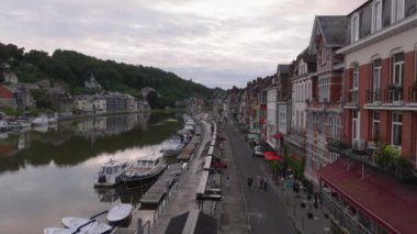 Belçika, Dinant 'taki Meuse Nehri' nin havadan görünüşü. Turistler su boyunca kaldırımda yürürler. Binalar, ağaçlar ve tekneler görünür..